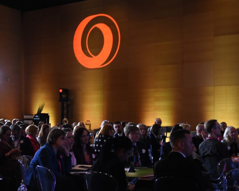 Zdjęcie w trakcie Kongresu PopScience - ludzie siedzacy na sali, na Ścianie logotyp inicjatywy